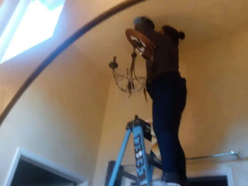 Electrician installing a chandelier in a Collinsville residence